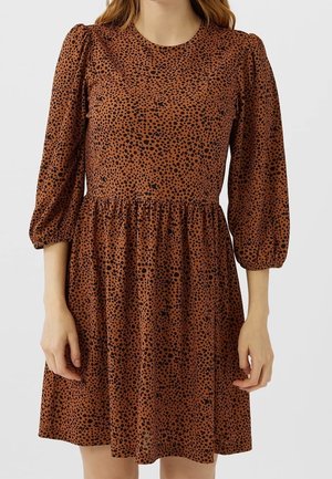 Robe marron avec un motif à pois noirs, col rond et manches bouffantes. Elle présente une taille froncée et une texture lisse.