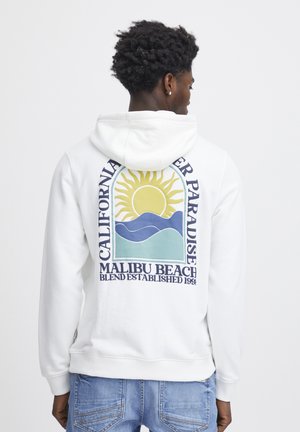 White hoodie featuring a colorful graphic of a sun and waves. Text reads "California" and "Malibu Beach," with a soft, textured fabric.