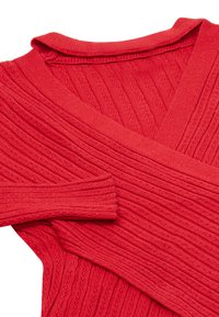 Rød ribbet sweater med v-hals, der har et struktureret strikmønster og lange ærmer. Stoffet virker blødt og strækbart.
