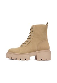 Masywne beżowe zamszowe botki za kostkę z okrągłym noskiem, sznurowanym przodem i grubą platformą z teksturowanym bieżnikiem.