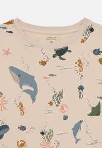 Beige organic cotton t-shirt with aquatic-themed print featuring whales, turtles, fish, and coral in colors like blue, pink, and green.