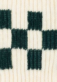 Tessuto lavorato a maglia verde e crema con un motivo a scacchi con quadrati alternati. Tesura a costine verticali in tutto il tessuto.