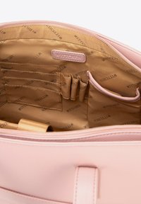 Vista interior de un bolso de cuero rosa que muestra un forro de tela beige con logo, múltiples compartimentos para tarjetas, soportes para bolígrafos y un pequeño bolsillo.