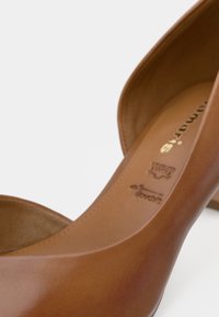 Καφέ δερμάτινο ψηλοτάκουνο παπούτσι με λεία υφή, ανοιχτές πλευρές και χρυσό ανάγλυφο λογότυπο μάρκας στην εσωτερική σόλα.