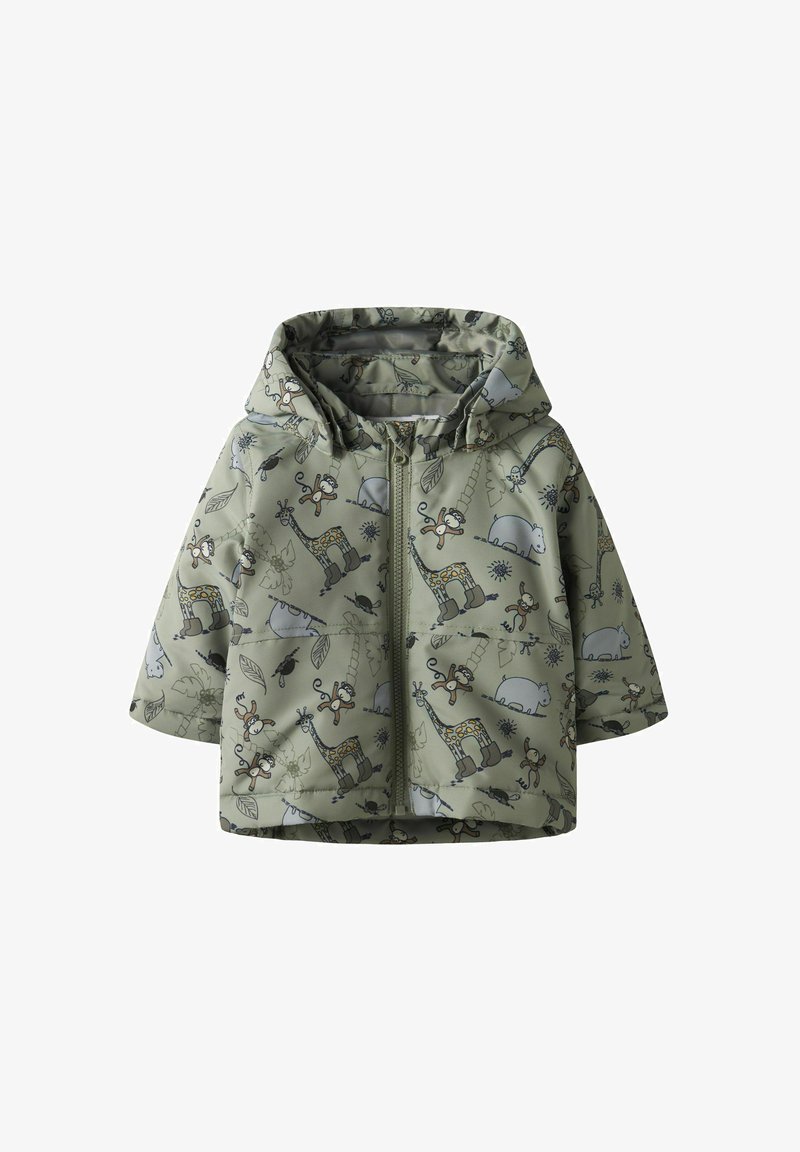 Veste verte arborant un imprimé animalier ludique avec des girafes, des singes et du feuillage. Le matériau semble texturé et imperméable, avec une fermeture éclair à l'avant.