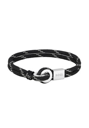 Pulsera de cuerda negra tejida con acentos blancos, cierre circular de plata y placa rectangular de plata grabada con el nombre de la marca "BOSS".