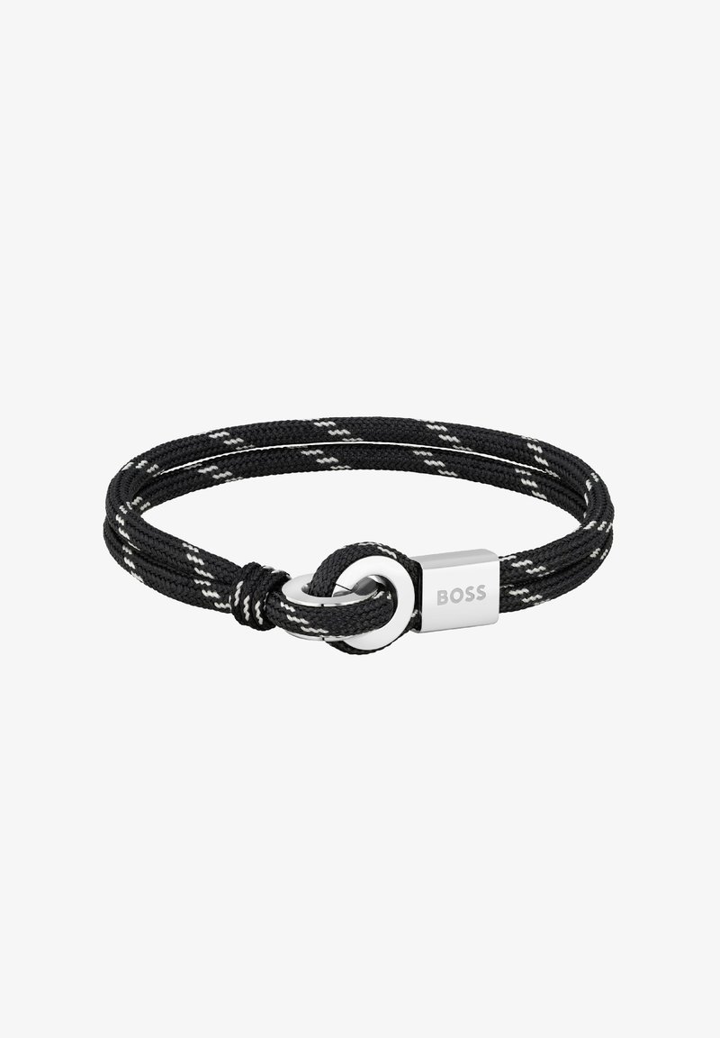 Bracelet en corde noire tressée avec accents blancs, fermoir circulaire en argent, et étiquette rectangulaire en argent gravée du nom de la marque "BOSS".