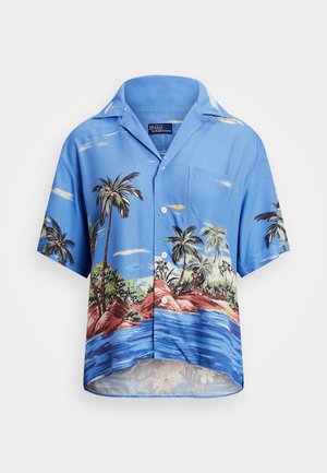 Chemise bleue à manches courtes avec des boutons, imprimée avec des palmiers, des rochers et des vagues de l'océan sur le tissu, avec une poche poitrine avant.