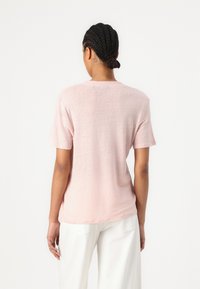Světle růžové tričko s krátkým rukávem vyrobené z měkké tkaniny s volným střihem. Jednoduchý design s kulatým výstřihem a jemnou texturou.