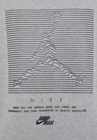 Grå t-shirt med en serie svarta horisontella linjer som bildar ett toppmönster, med tryckta texter "NIKE" och "JUMP MAN" logotyper.