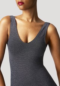 Camisole métallique noir avec un décolleté en V profond, texture lisse et larges bretelles, s'ajustant étroitement au corps, mettant en valeur une surface brillante et réfléchissante.