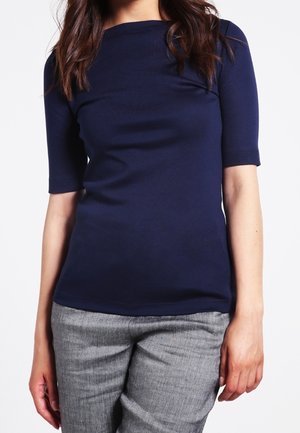 Granatowa krótka bluzka z krótkim rękawem i okrągłym dekoltem, wykonana z miękkiego materiału, zestawiona z szarymi, teksturowanymi, dopasowanymi spodniami.