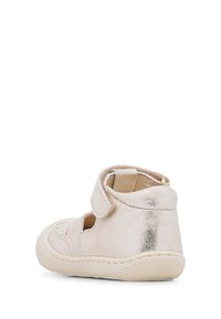 Chaussure pour tout-petits en métal doré avec un bout arrondi, des découpes et une sangle Velcro. La semelle est de couleur crème avec une finition texturée.