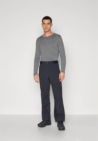 Grijze lange mouwen shirt gecombineerd met donkere cargobroek. De broek heeft meerdere zakken, een rechte pasvorm en is gemaakt van duurzaam materiaal. Zwarte schoenen.