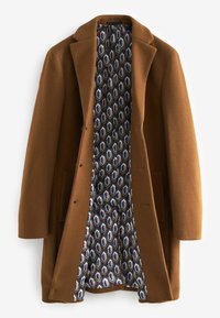 Manteau long en laine marron avec doublure intérieure à motif géométrique dans des tons de bleu, blanc et marron, suspendu ouvert sur fond blanc.