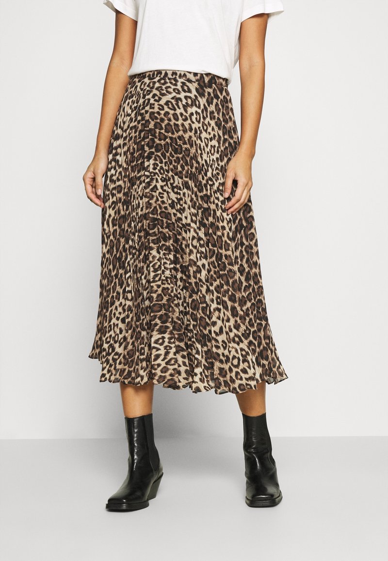 Jupe midi plissée à imprimé léopard dans des tons beige et marron, au design fluide, associée à des bottines noires.