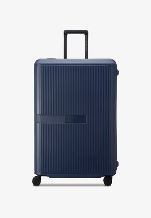 Valise rigide de couleur bleu foncé, avec une texture à rainures verticales, une poignée robuste et quatre roues à roulement fluide pour une mobilité aisée.
