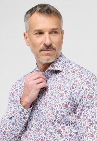 Blomstret skjorte med hvid bund, prydet med rosa, blå og grønne blomster mønstre. Stoffet ser glat og let ud, med en klassisk krave.