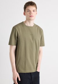Oliven grønn bomulls T-skjorte med rund hals, korte ermer, og en liten preget logo. Myk tekstur, avslappet passform, og minimalistisk design.