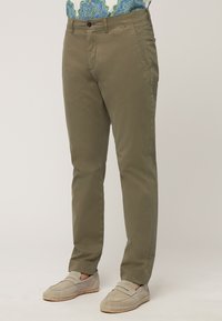 Olive green chinos made of lightweight fabric, featuring side pockets, a button closure, and a straight-leg design. Paired with beige loafers.