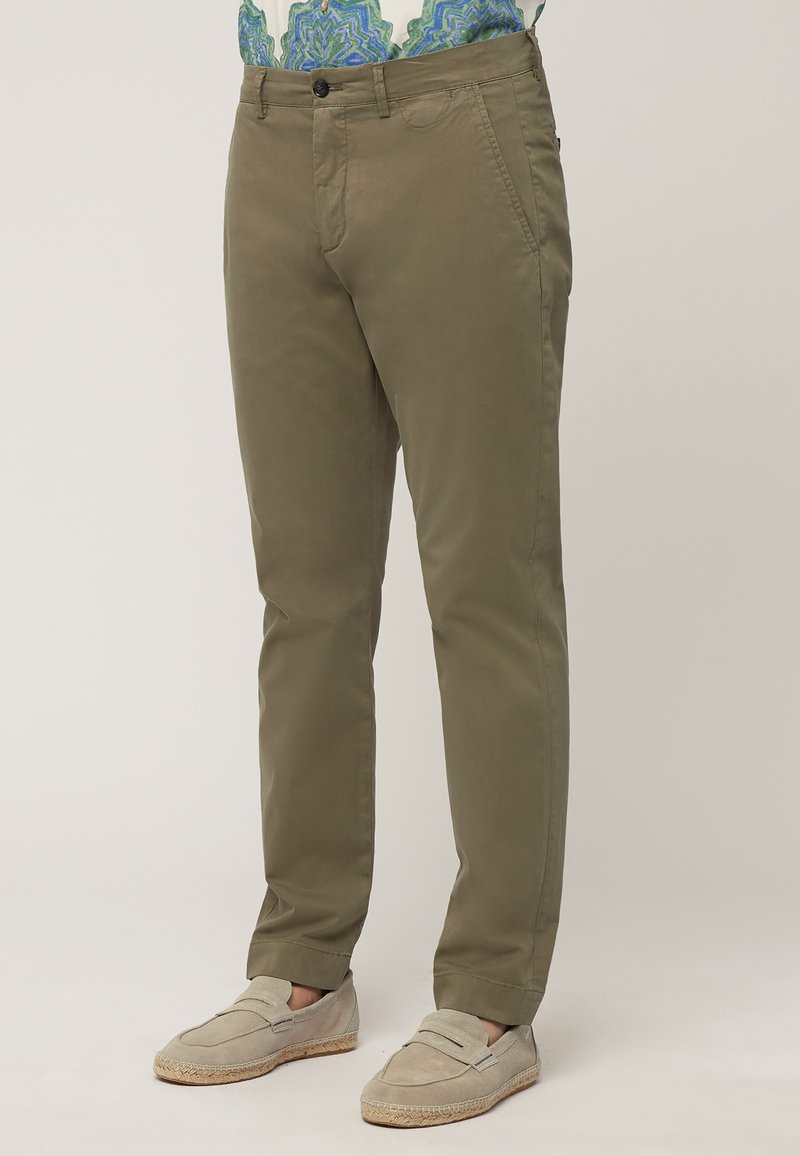 Olive green chinos made of lightweight fabric, featuring side pockets, a button closure, and a straight-leg design. Paired with beige loafers.