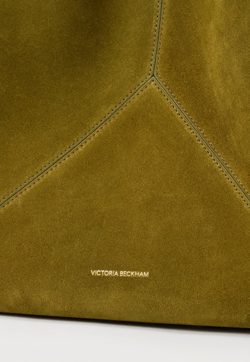 Olive green suede leather handbag with visible stitching forming geometric shapes and "Victoria Beckham" embossed in gold lettering.