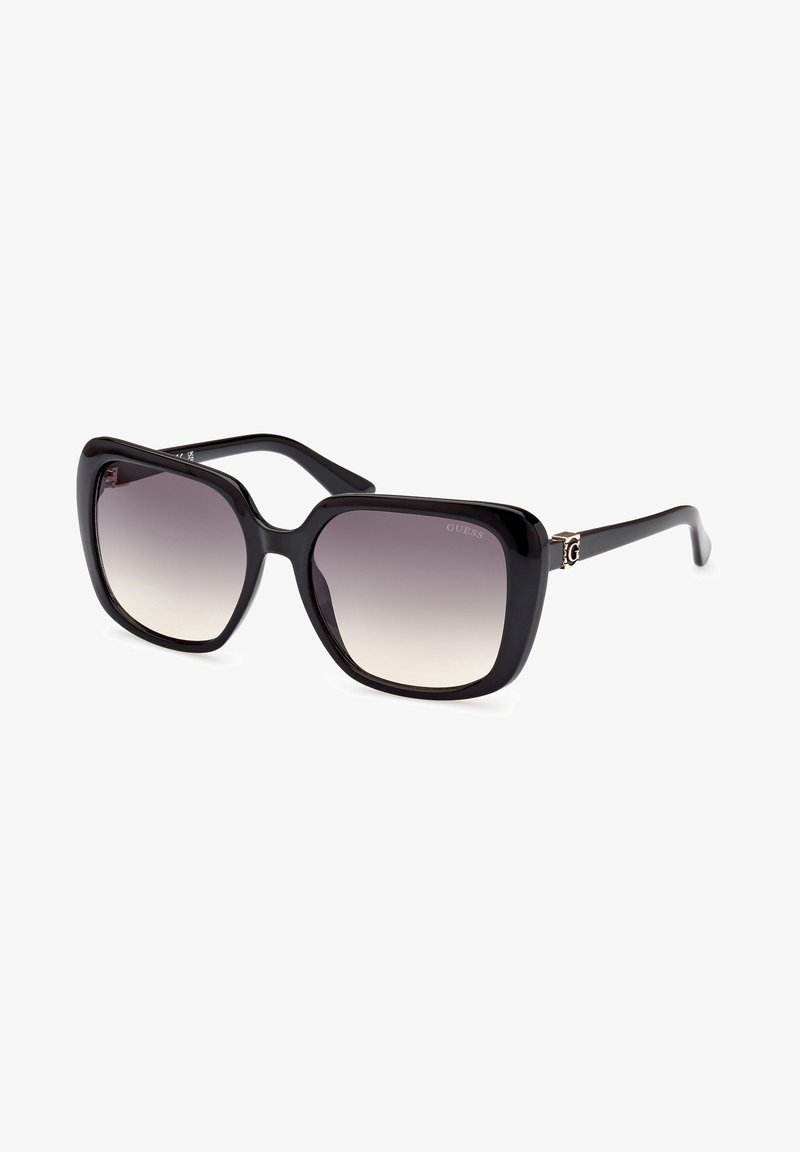 Black oversized sunglasses with a gradient lens. Features thick plastic frames and a small metallic logo accent on the temple.
