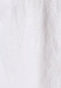 Tessuto di lino bianco con una consistenza liscia, caratterizzato da un aspetto leggermente stropicciato e da fibre naturali fini.