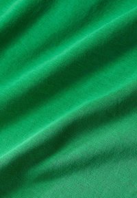 Groene stof met een gladde textuur, voorzien van afwisselende lichte en donkere strepen, die zachtjes in delicate vouwen hangt.