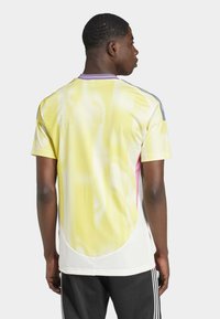 Kortärmad träningsskjorta i gult och rosa med nätstruktur, cirkulära mönster och blå detaljer på axlarna.