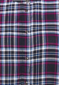 Hemd mit Knopfleiste in einem mehrfarbigen Karomuster mit Marineblau, Weiß, Rosa und Blau. Hervorzuhebende Details sind die metallischen Knöpfe.