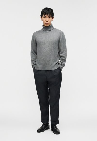 Γκρι πουλόβερ με ζιβάγκο, ribbed μανσέτες και τελείωμα, σε συνδυασμό με σκούρο παντελόνι με λεπτές ρίγες και μαύρα δερμάτινα παπούτσια. Απλός, εφαρμοστός σχεδιασμός.