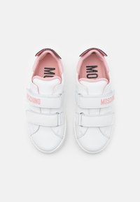 Bílé kožené tenisky s růžovými akcenty a suchými zipy, s zaoblenou špičkou, polstrovaným límcem a brandingem "MOSCHINO" na páscích.