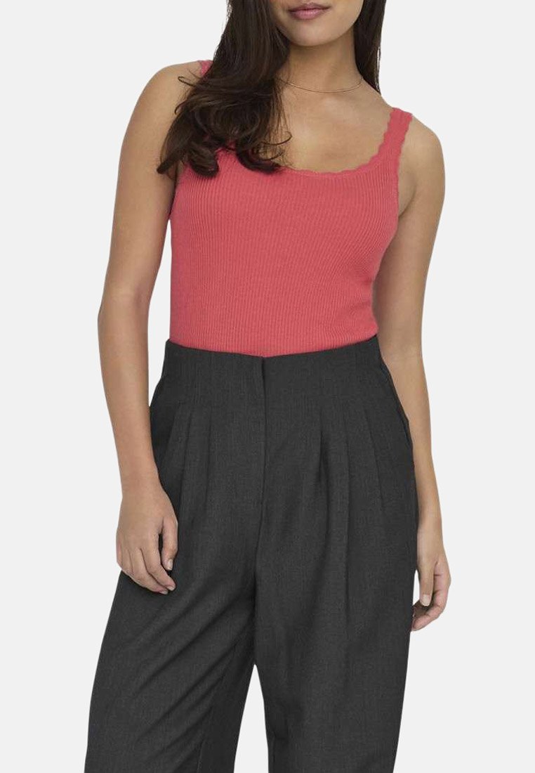 Débardeur corail à l’aspect côtelé avec des bords festonnés, associé à un pantalon gris plissé taille haute, mettant en valeur une texture douce et une coupe ajustée.