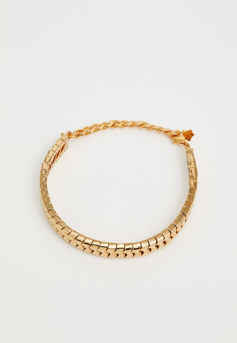 Zlatý tónovaný kovový náhrdelník s čtvercovými články a zkrouceným řetězem. Obsahuje bezpečné zapínání a hladký, lesklý povrch.