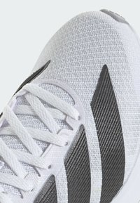 Weißer Sportschuh mit Obermaterial aus Mesh und schwarzen strukturierten Akzenten, ausgestattet mit flachen weißen Schnürsenkeln und einer konturierten Sohle für Unterstützung.