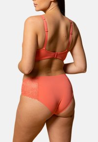 Ensemble de lingerie corail comprenant un soutien-gorge lisse et un slip taille haute avec des accents en dentelle, mettant en avant un design sans couture et des bretelles réglables.