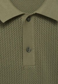 Polo shirt verde oliva con un design a maglia aperta e testurizzata. Presenta un colletto classico, due bottoni scuri e motivi a maglia a contrasto.