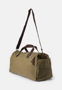 Olivengrøn kanvas duffel taske med brune læderdetaljer, dobbelte håndtag og en justerbar skulderrem. Har en lynlåsåbning.