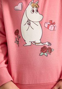 Roze sweatshirt met een wit cartoonfiguurtje, rozen en een cadeautjesontwerp. De stof lijkt zacht, met geribbelde boorden en zoom.