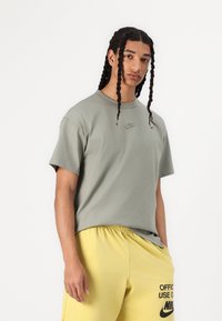 Lichtgroen katoenen t-shirt met een klein Nike-logo op de borst, gecombineerd met gele shorts met zwarte branding. Korte mouwen, losse pasvorm.