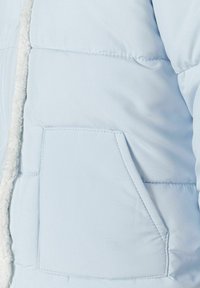 Svijetloplava pufasta jakna s teksturiranim, krznenim ovratnikom, džepom na lijevoj strani i ušivenim detaljima na tkanini.