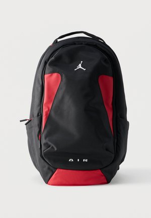Zaino nero e rosso con manico superiore, logo Jordan, tasca frontale con cerniera e scritta "AIR" sulla parte inferiore, mostrato su uno sfondo neutro.