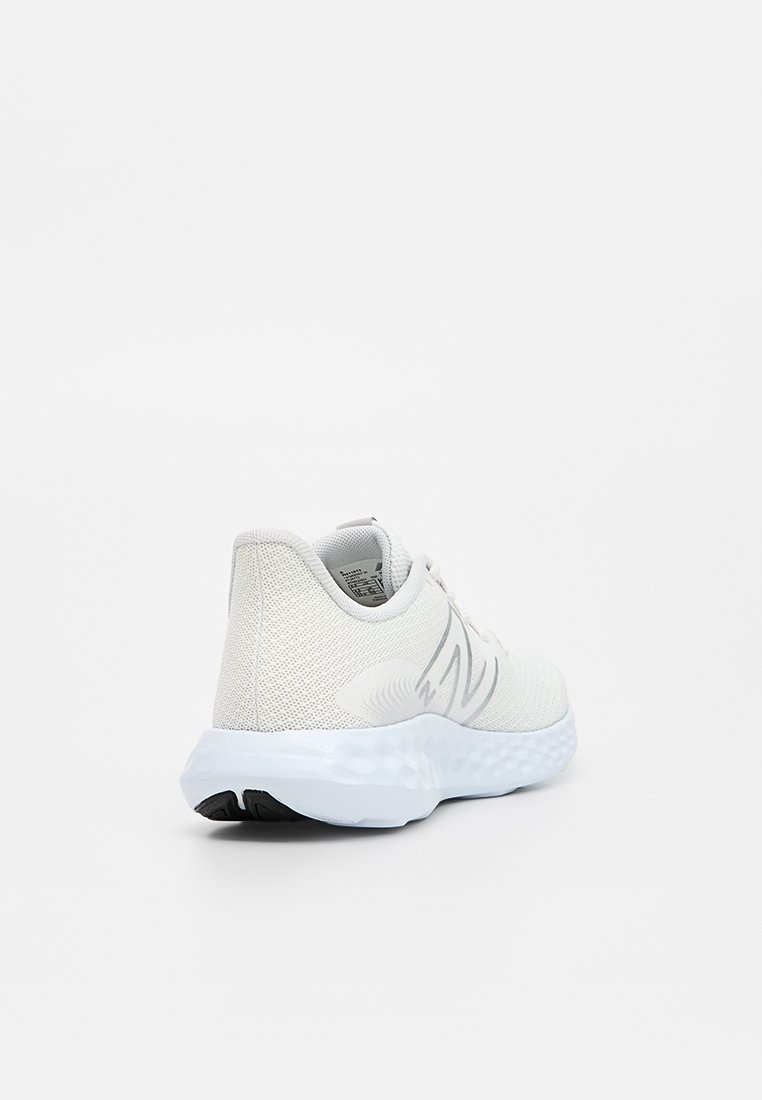 Chaussure de sport blanche avec une tige en maille texturée, un col rembourré et une semelle amortissante. Présente un détail logo subtil sur le côté.