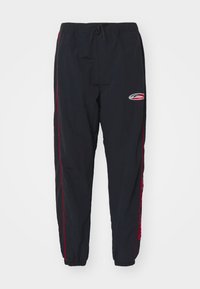 Sorte træningsbukser lavet af letvægtsmateriale, med røde sidelister og et logo på venstre lår. Elastisk talje med snore.