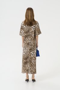 Maksi haljina s leopard uzorkom, kratkim širokim rukavima, opuštenog kroja i prorezom straga. Uparen s malom plavom torbicom i crnim štiklama.