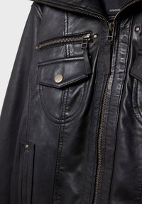 Schwarze Lederjacke mit Metallreißverschluss, Reißverschlusstasche auf der Brust, Klappentasche mit Druckknopf und detaillierter Naht.