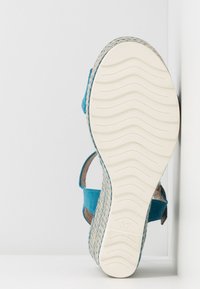 Tyrkysové sandály s pletenou jute platformou a bílou strukturovanou podrážkou. Nastavitelný popruh na boku, velikost označena jako 37.