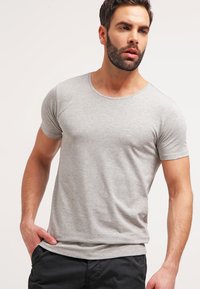 Tricou gri cu mânecă scurtă, cu guler rotund, fabricat din material moale de bumbac, cu o croială standard și o textură netedă. Nu are modele vizibile.