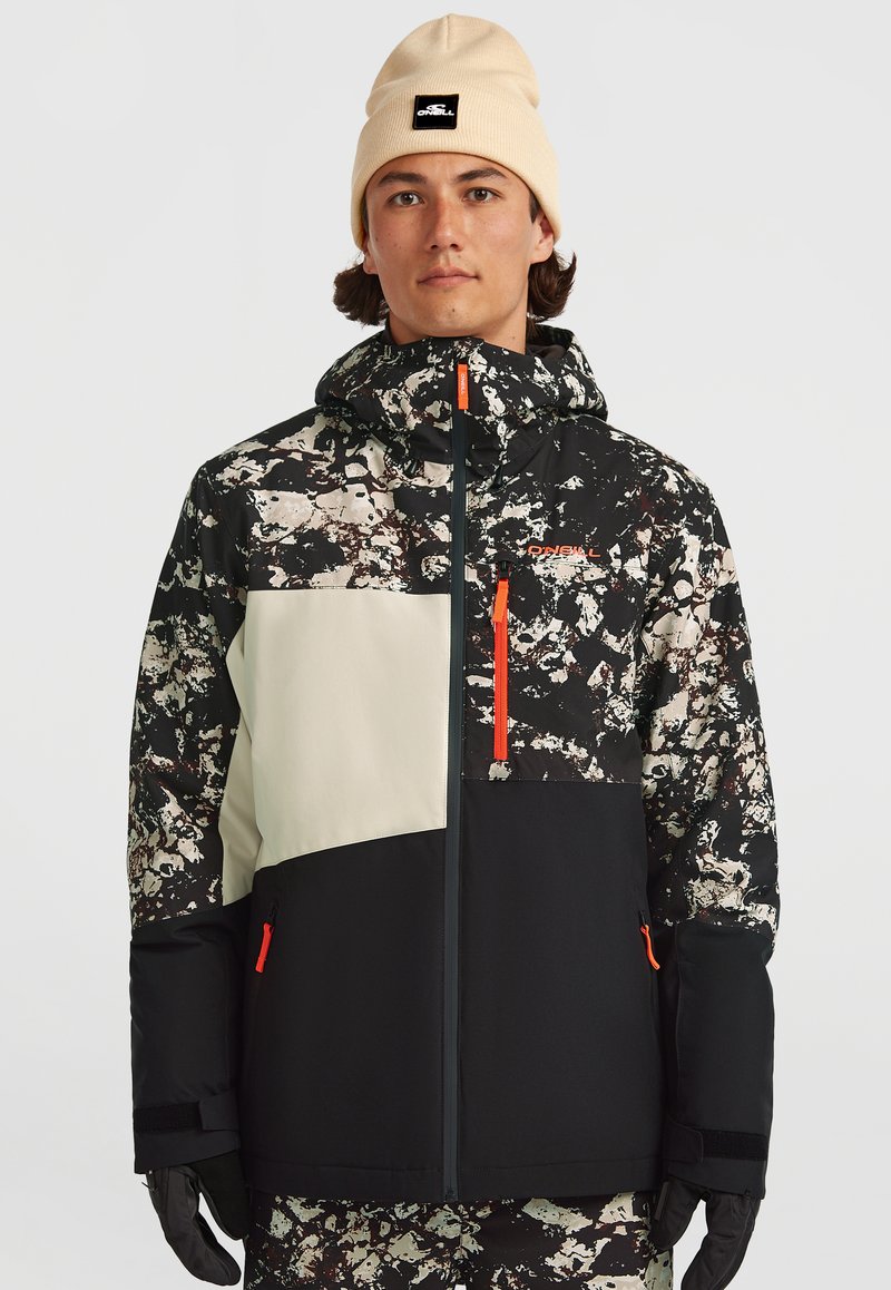 Sneeuwjacket met een zwart, wit en beige abstract patroon, voorzien van oranje ritssluitingen en accenten; inclusief een capuchon en verstellbare manchetten.